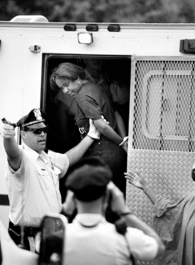 A U.S. Park Police officer prepares to move a handcuffed Toni Quick to another van. She was among those arrested in the protest on Pennsylvania Avenue by D.C. residents.