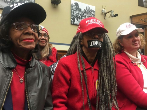Anise Jenkins, center, a native Washingtonian, wears black tape over her mouth that reads, "Free DC," as she and her neighbors, Ms. Power, left, who wouldn't give her first name, and Karen Szulgit, watch a congressional hearing aimed at overturning a District of Columbia law that would legalize assisted suicide. Rep. Jason Chaffetz, a Utah Republican and chairman of the House Oversight and Government Reform Committee, was the target of their ire for worrying about D.C. laws and not investigating Russia's interference in the presidential election. "He needs to do his job," Jenkins said.